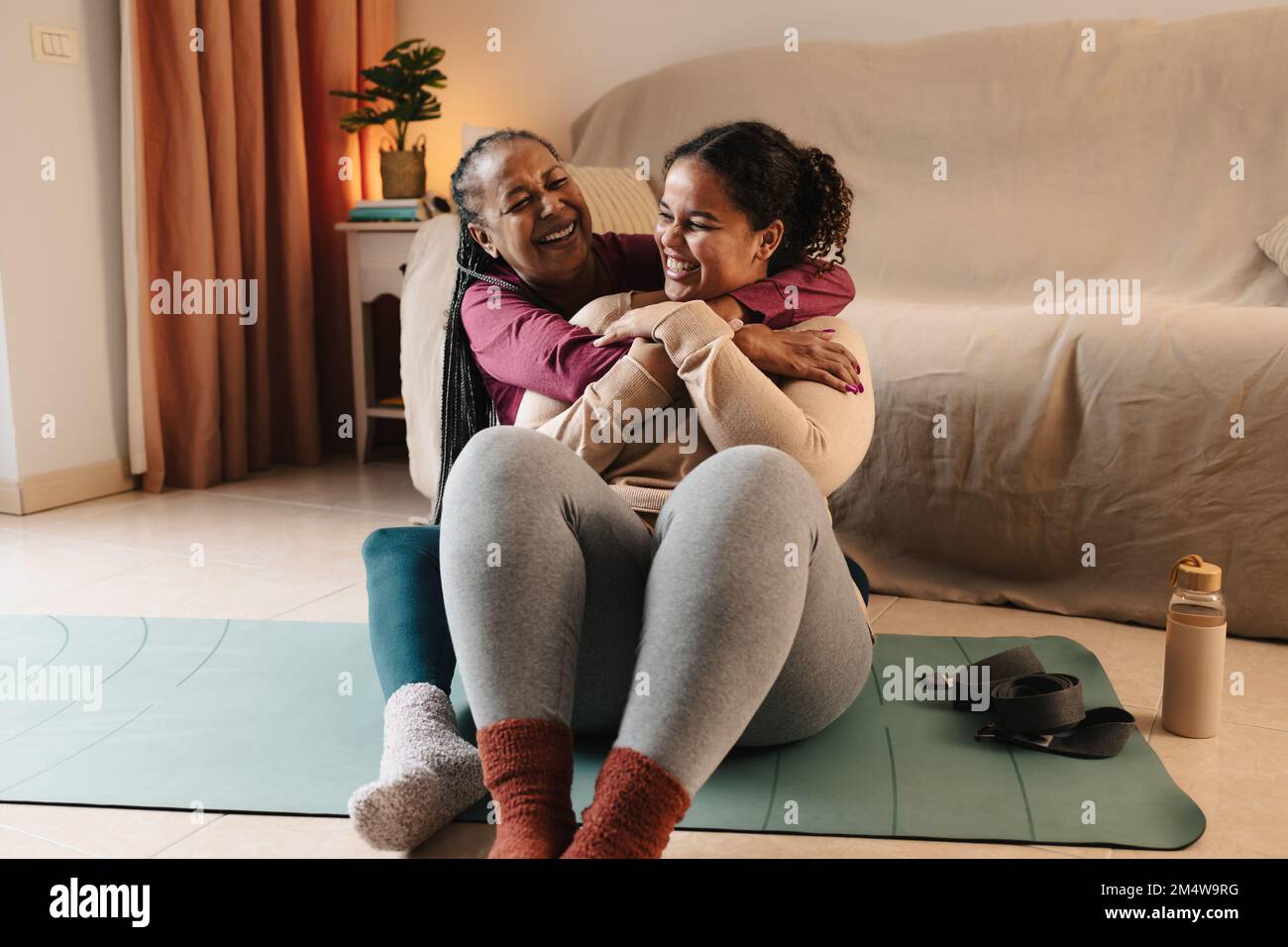 Madre e hija africanas felices que tienen un momento tierno mientras hacen pilates en casa Foto de stock