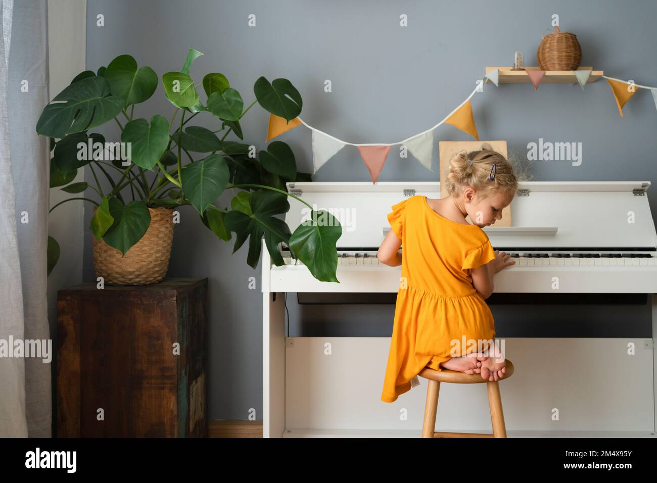 Muchacha en el taburete tocando el piano en casa Fotografía de stock - Alamy