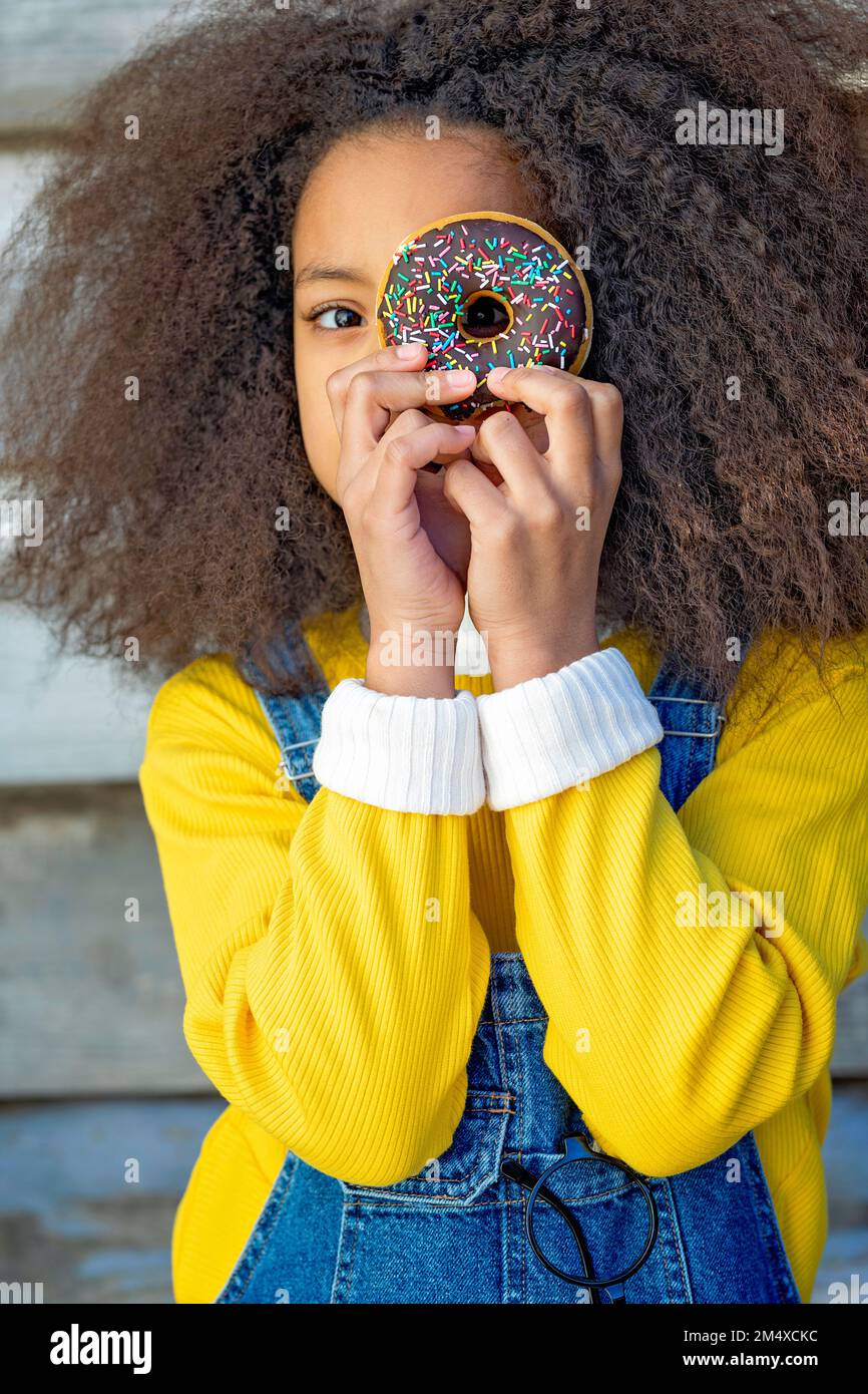 Chica mirando a través del agujero de donut Foto de stock