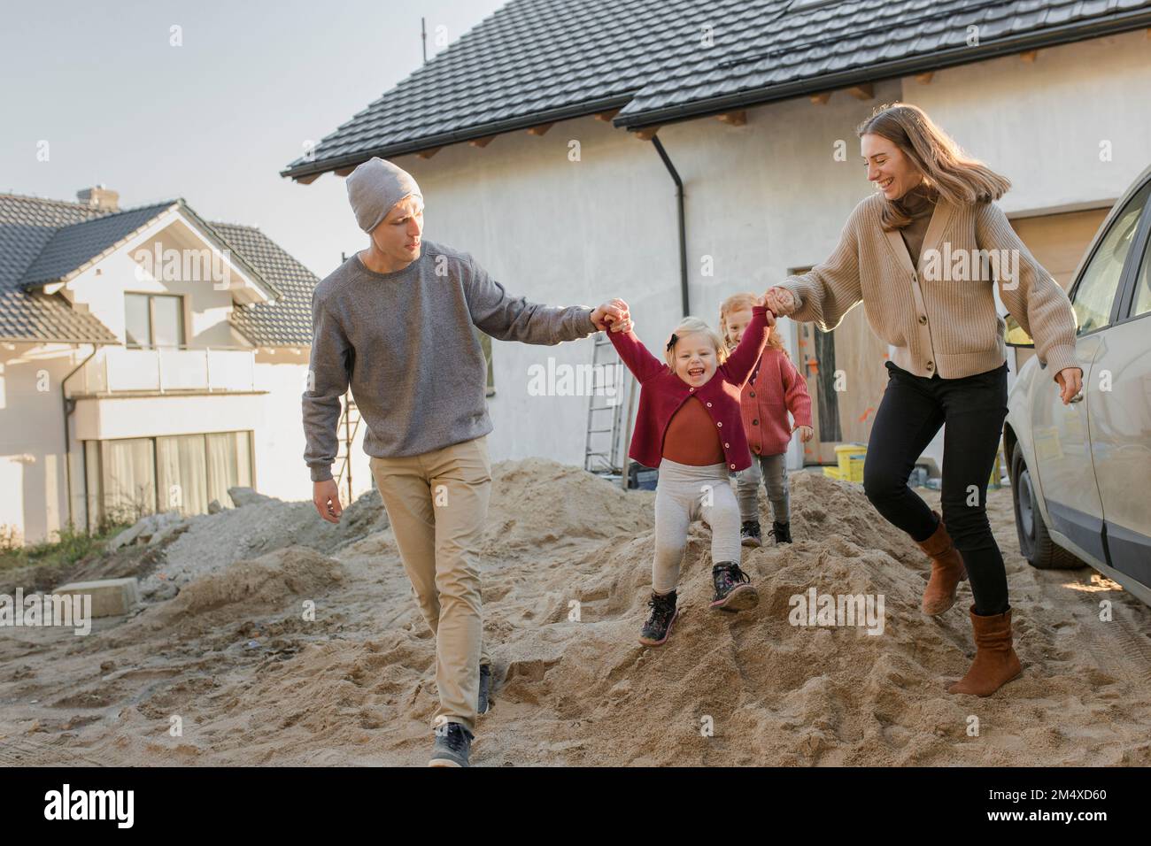 Padres con hijas en un montón de cemento fuera de la casa Foto de stock