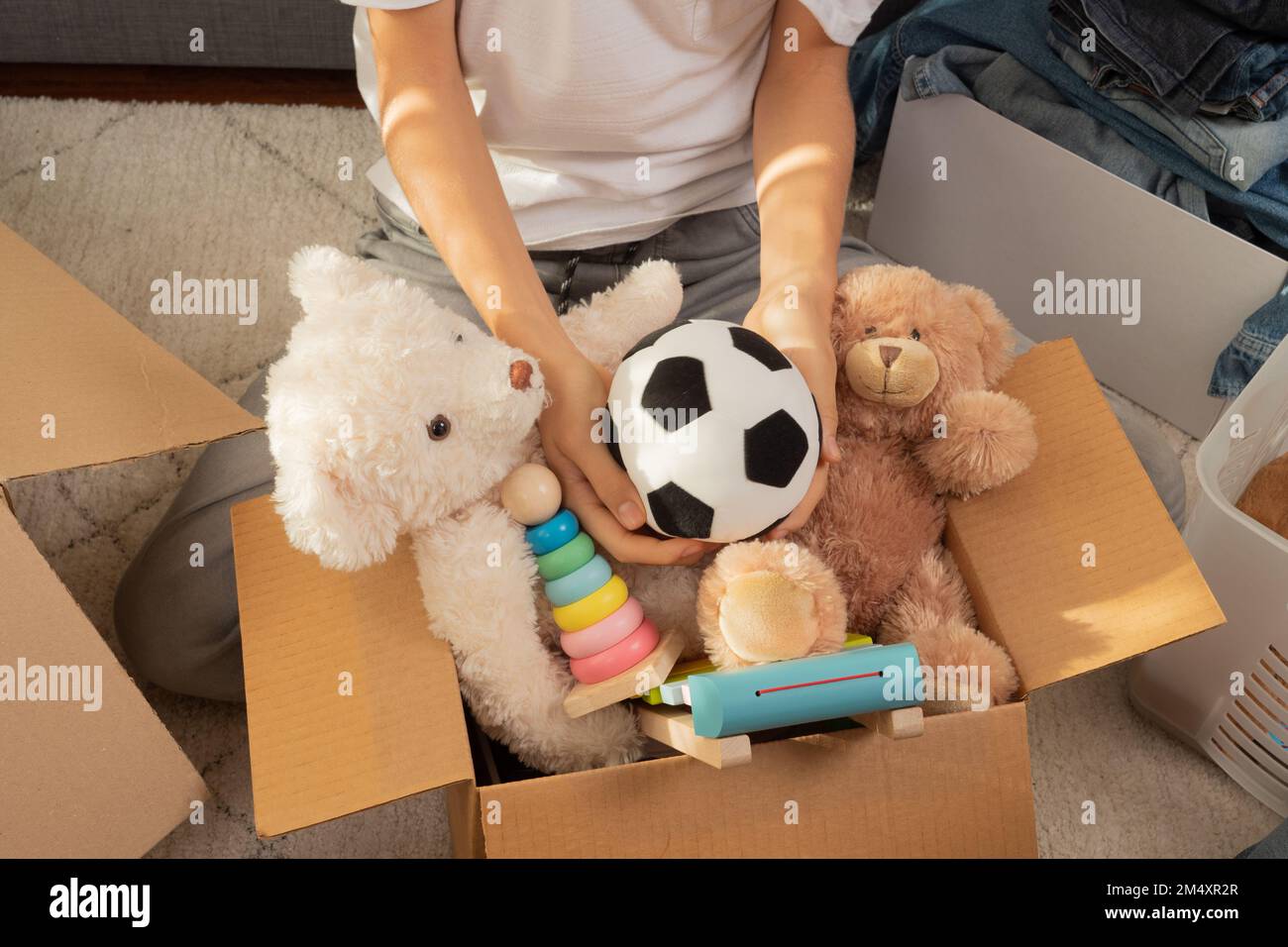 Adolescente clasificando y recoger juguetes de niño, ropa en cajas en casa. Donaciones para caridad, ayudar a familias de bajos ingresos, deslutar casa, vender en línea Foto de stock