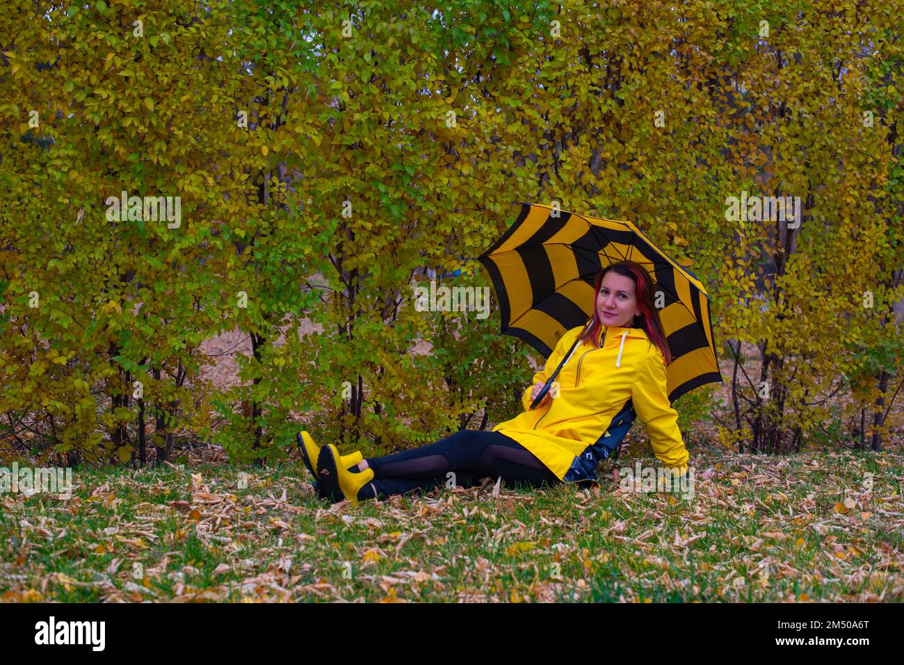 Una joven con chubasquero amarillo y paraguas se está divirtiendo mientras  camina por la ciudad en un ambiente tranquilo bajo la lluvia. Paseo,  lluvia, ciudad Fotografía de stock - Alamy