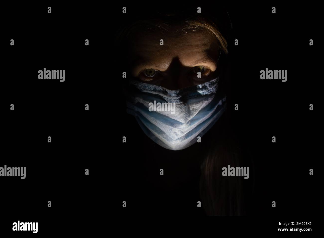 chica en máscara médica en una habitación lánguida sola en cuarentena Foto de stock