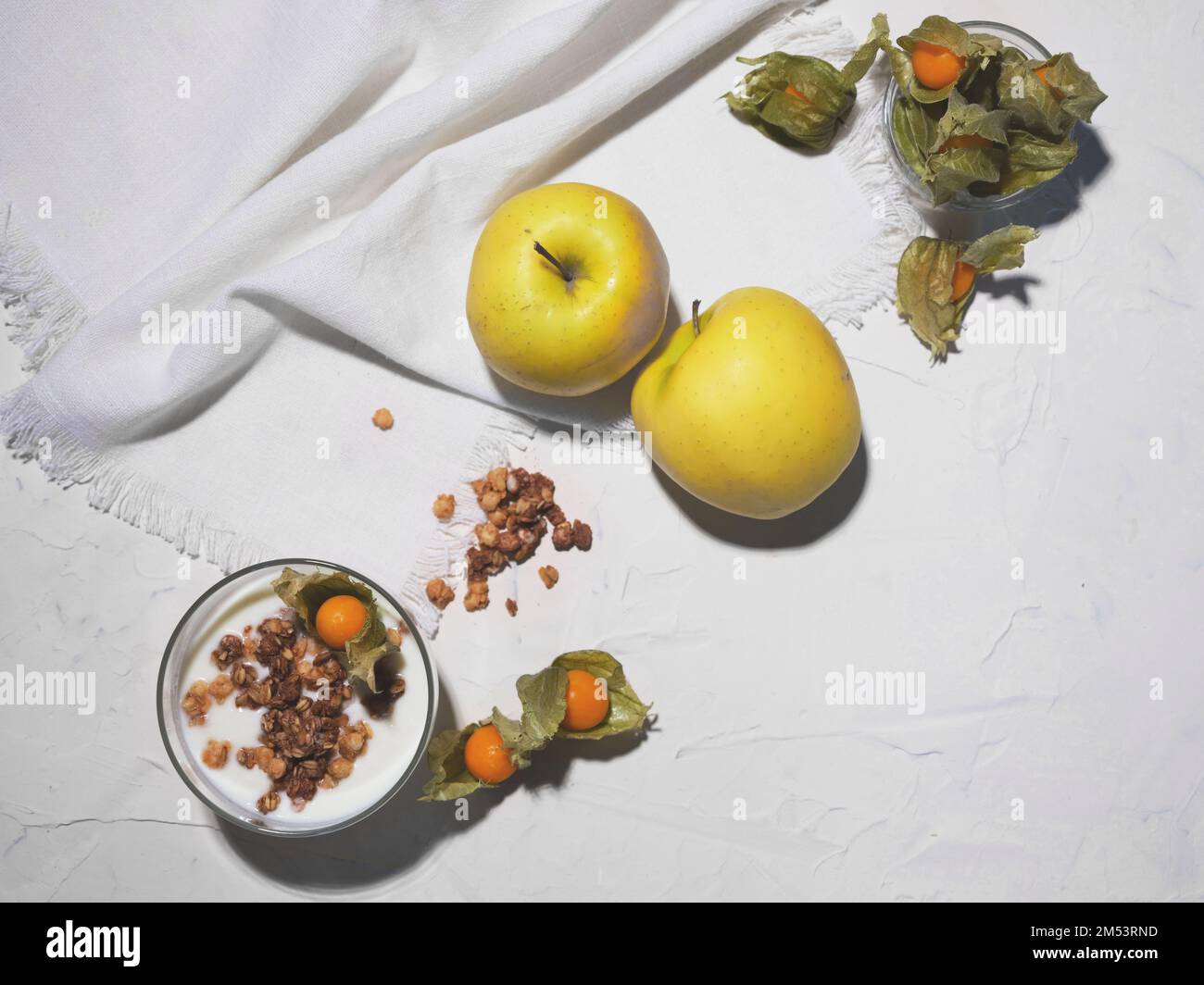 Desayuno saludable con yogur, cereales y frutas como physalis y manzanas Foto de stock