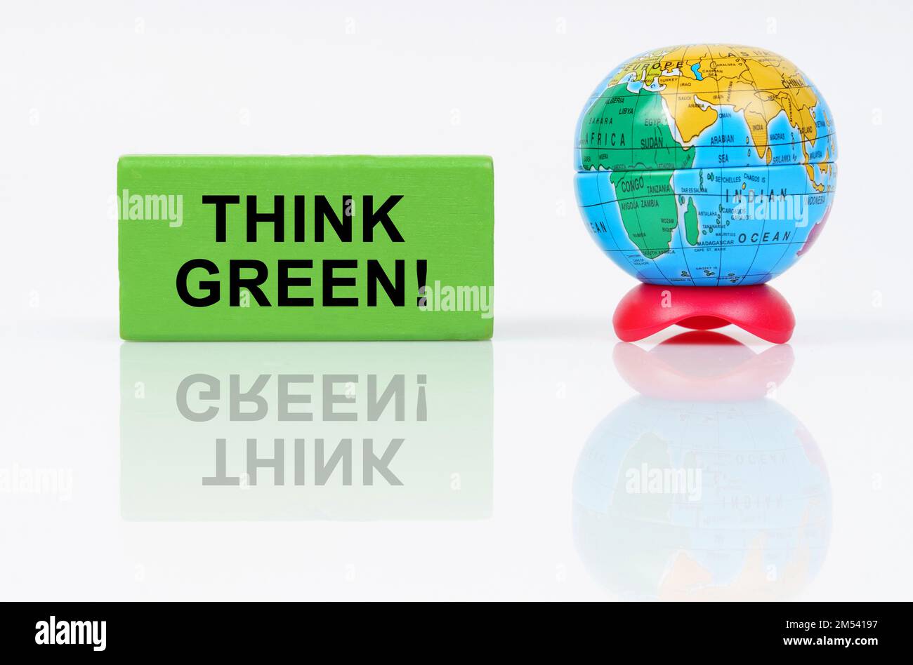 Concepto ecológico. En una superficie reflectante es un globo y un signo verde con la inscripción - Piensa en verde Foto de stock