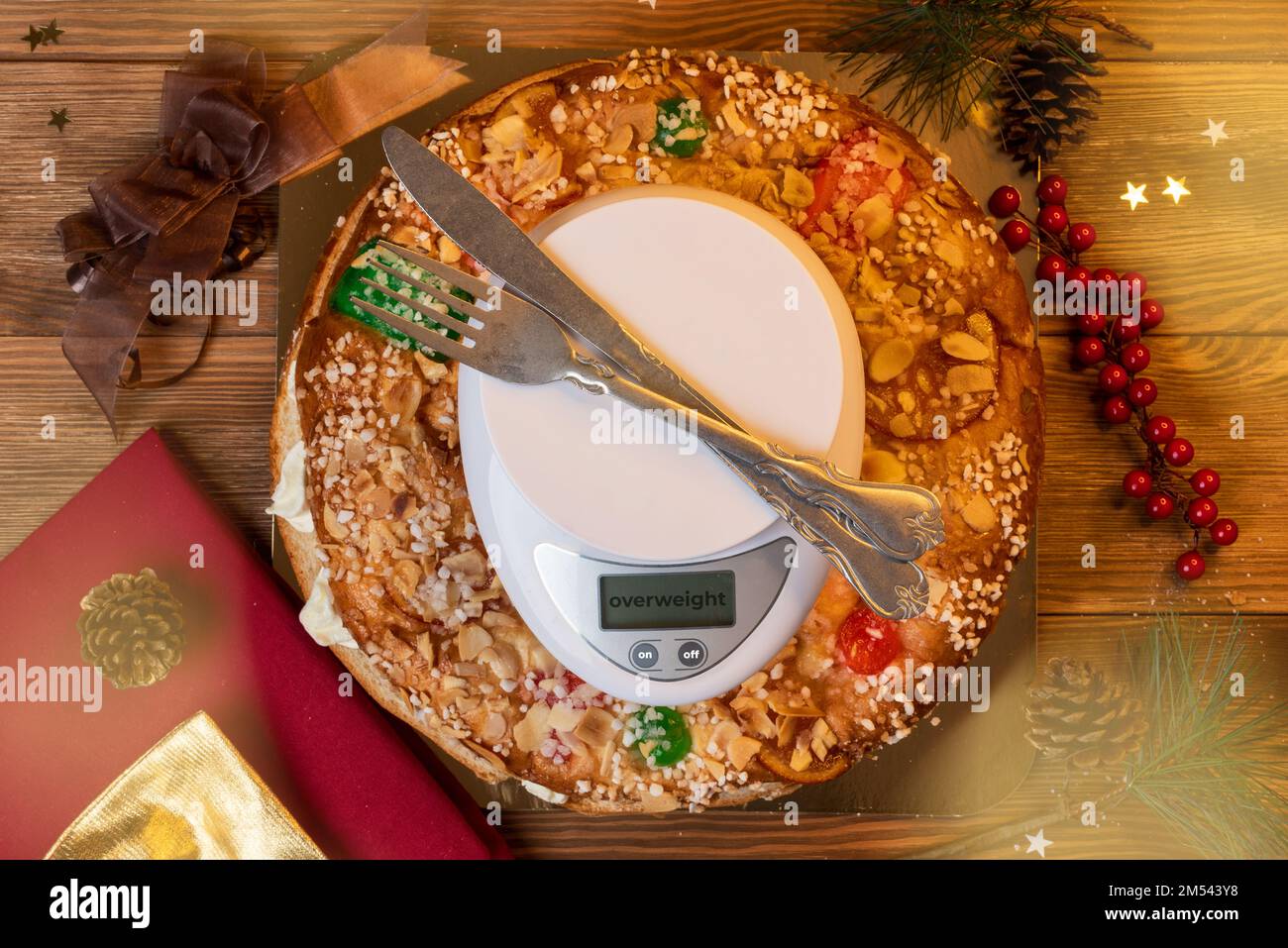 Pastel de Epifanía 'Roscon de Reyes' junto a una escala. Concepto de sobrepeso debido a la ingesta de dulces en Navidad. Peligro de engordar al comer azúcar Foto de stock