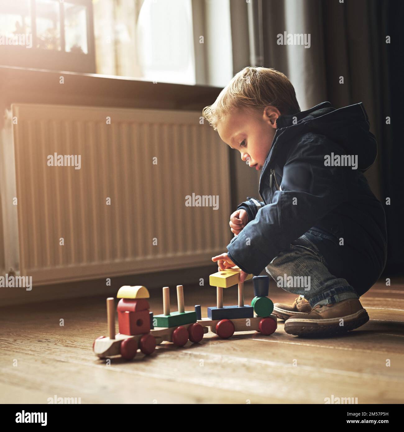 El choo-choo es su juguete favorito. un niño adorable jugando con su tren de juguete en casa. Foto de stock
