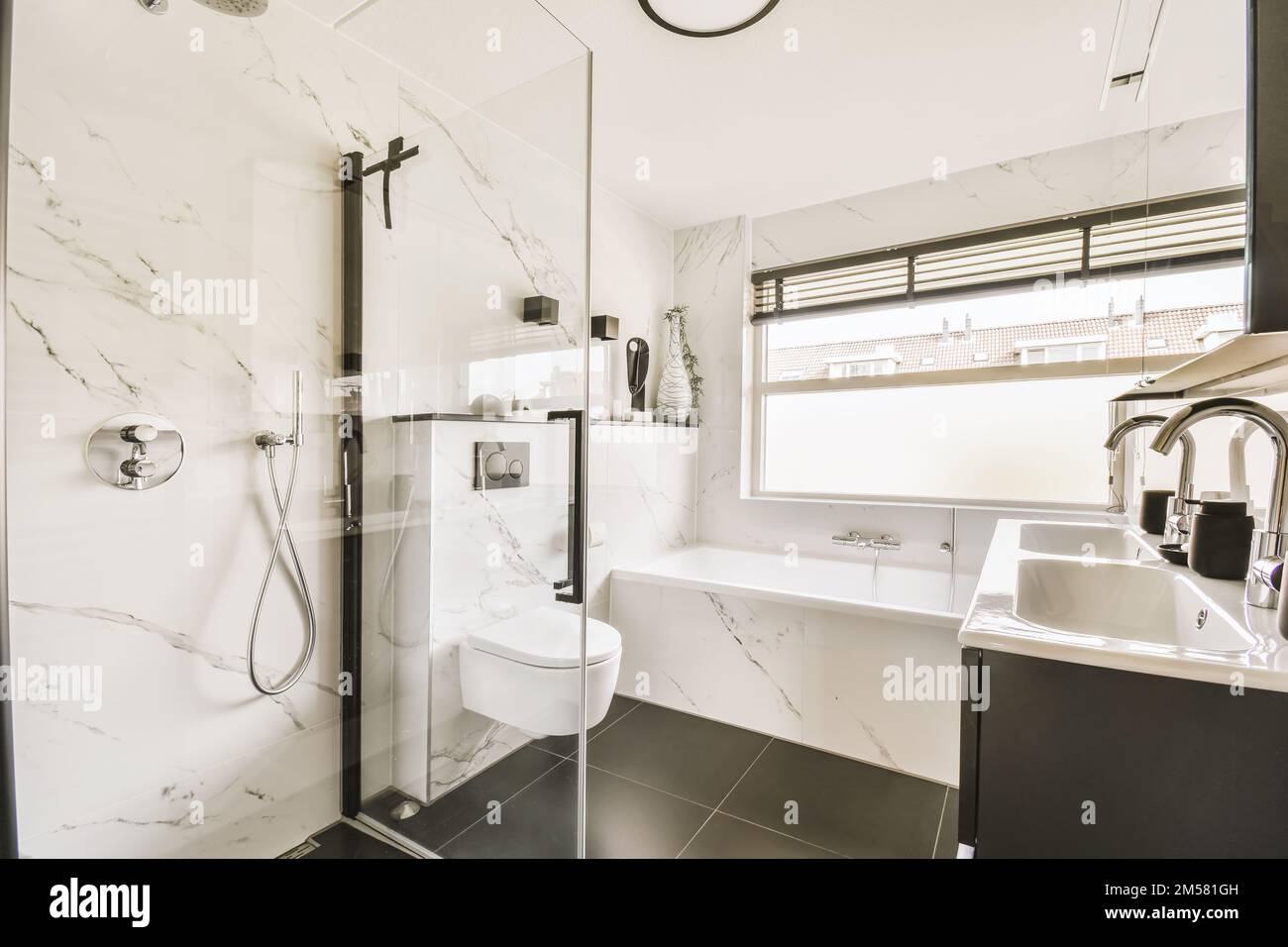 un moderno cuarto de baño con azulejos de mármol blanco y negro en las paredes, ducha y wc en la zona de la esquina Foto de stock