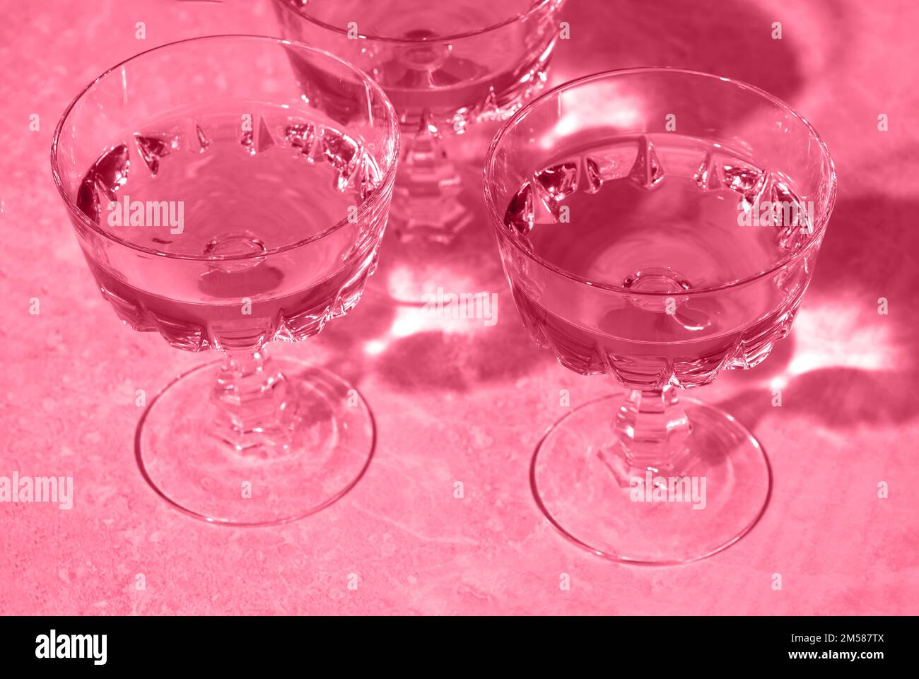 https://c8.alamy.com/compes/2m587tx/tres-copas-de-cristal-de-vino-espumoso-o-champan-imagen-tonificada-en-color-magenta-de-moda-del-ano-2023-composicion-creativa-minima-con-espacio-de-copia-2m587tx.jpg