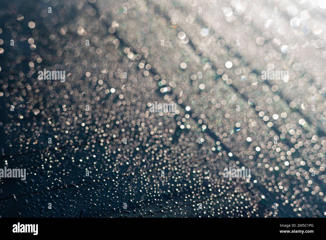 La condensación o la lluvia cae en la ventana trasera del coche en invierno en una mañana soleada Foto de stock