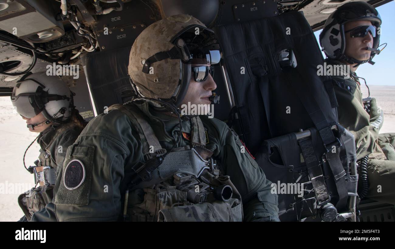EE.UU Janae Jarnagin (izquierda), el sargento Brock Gilbert (centro), los jefes de tripulación y el sargento David Smaus, mecánico de línea de vuelo, el Escuadrón de Evaluación de Operaciones y Pruebas de la Marina 1 (VMX-1), observan la coordinación de huelga y el entrenamiento de reconocimiento desde el interior de un Venom UH-1Y cerca de El Centro, California, 10 de marzo de 2022. El propósito de este ejercicio era proporcionar oportunidades de familiarización con los sistemas aéreos no tripulados y las aeronaves tripuladas que trabajan simultáneamente. Foto de stock