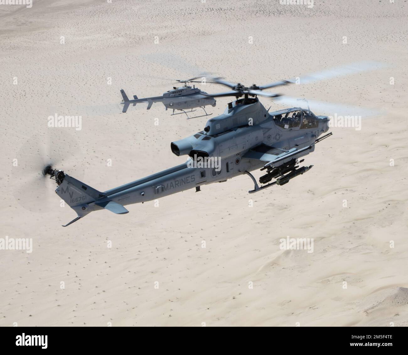 Un AH-1Z VIPER (FRENTE) con el Escuadrón de Evaluación Operacional y de Pruebas de la Marina 1 (VMX-1), y un helicóptero MQ-8C Fire Scout no tripulado asignado al Escuadrón de Combate Marítimo de Helicópteros 23 (HSC-23), realizan la Coordinación de Ataque y Entrenamiento de Reconocimiento cerca de El Centro, California, el 10 de marzo de 2022. El propósito de este ejercicio era proporcionar familiarización y desarrollo de conceptos de trabajo en equipo tripulado-no tripulado. Foto de stock
