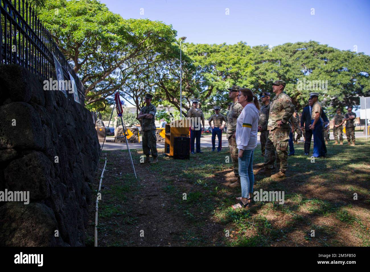 Militares y civiles estadounidenses se reúnen frente a un retrato del capitán Jeffrey A. Borchers durante una ceremonia de conmemoración frente a Borchers Gate, Base Conjunta Pearl Harbor-Hickam, Hawái, 11 de marzo de 2022. Los miembros del servicio se reunieron para honrar y recordar el servicio de Borchers en los Estados Unidos Cuerpo de Marines. Borchers, de quien se llamó la puerta, fue asesinado a tiros el 12 de marzo de 1990 mientras estaba de pie en lo que entonces se llamaba Puesto 19. Foto de stock