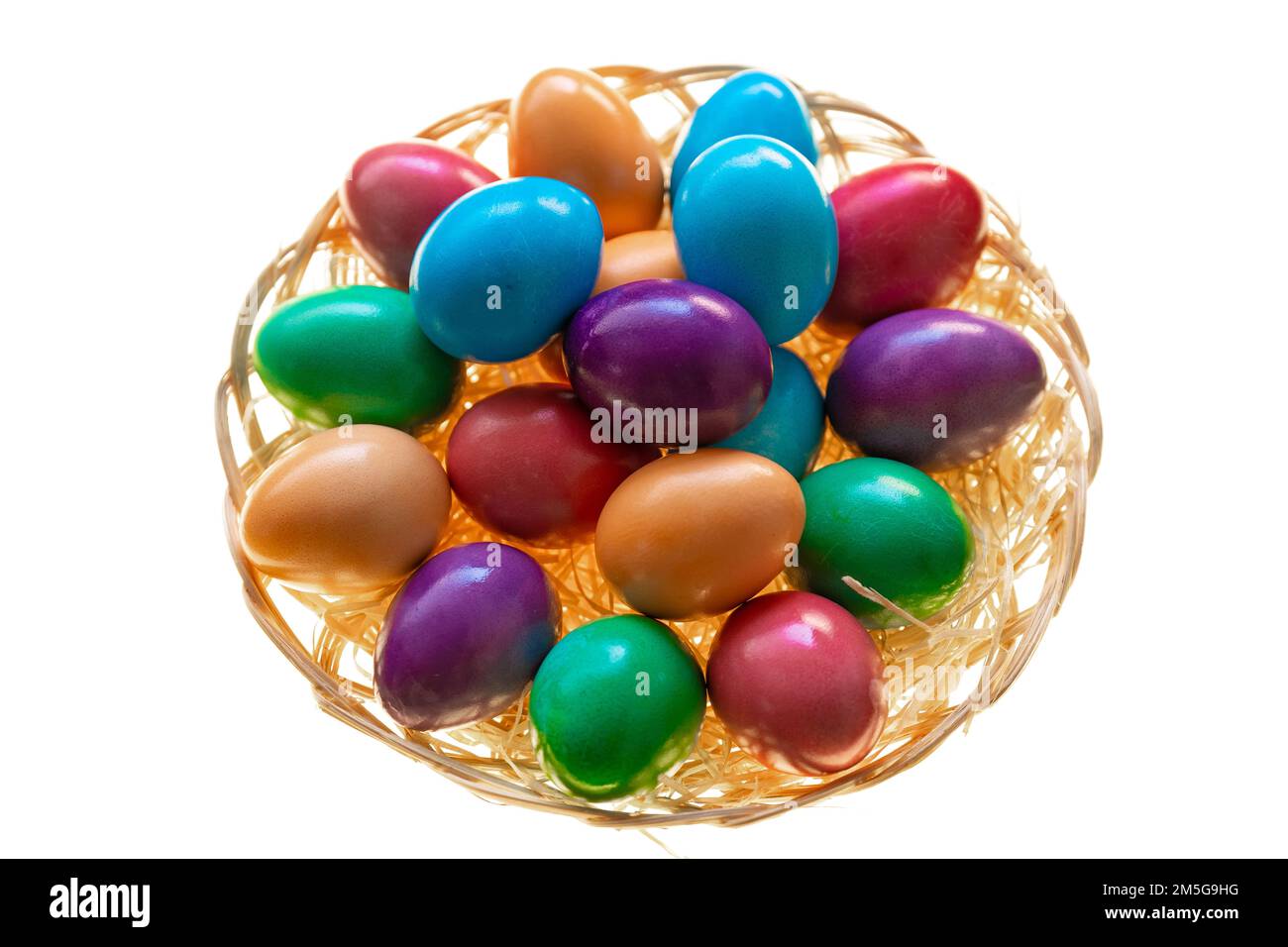 Huevos pintados en un cuenco de mimbre sobre un fondo blanco.Comida de Pascua. Símbolo de fiesta religiosa de primavera. Tradición de Pascua. Tradición cristiana y católica Foto de stock