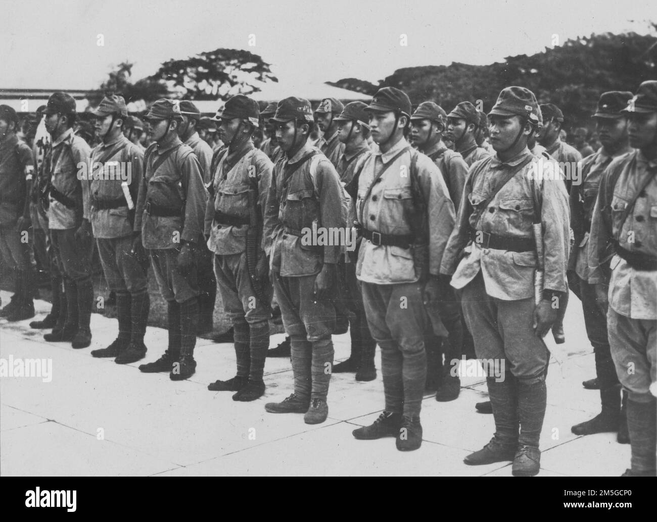 Guerra del Pacífico, 1941-1945. Voluntarios aborígenes taiwaneses del Ejército Imperial Japonés conocidos como los Voluntarios Takasago (高砂義勇隊) asisten a una ceremonia de premiación en reconocimiento a su distinguido servicio en Nueva Guinea, febrero de 1944. Tenga en cuenta los cuchillos de servicio tradicionales taiwaneses fijados a sus correas. Los Voluntarios Takasago eran conocidos por su aptitud en la guerra de la selva, sirviendo con distinción en una variedad de roles de apoyo y combate de primera línea durante la Guerra del Pacífico. Foto de stock