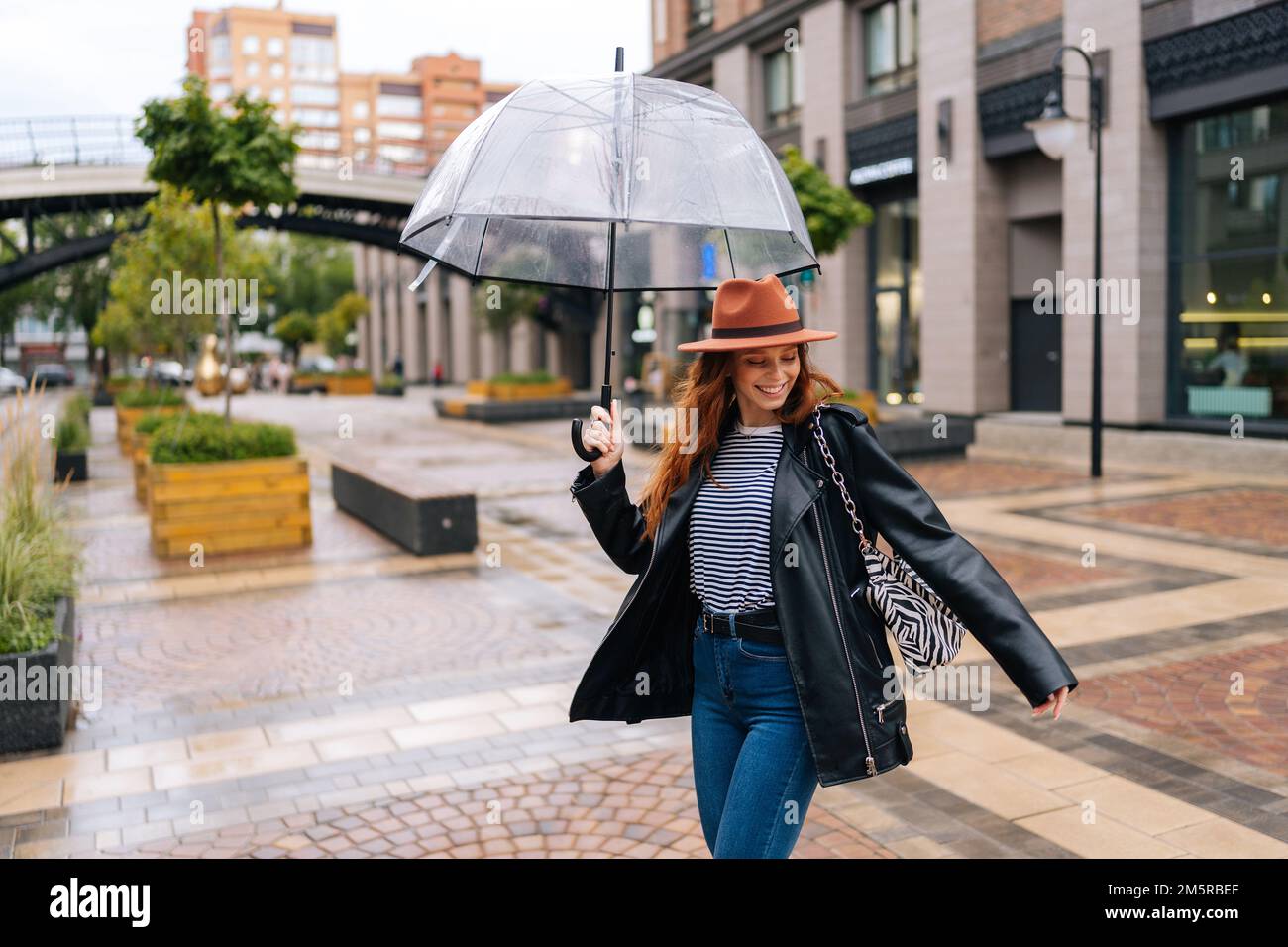 Hombre joven elegante en sombrero negro y ropa con paraguas en manos al  aire libre en la ciudad Fotografía de stock - Alamy