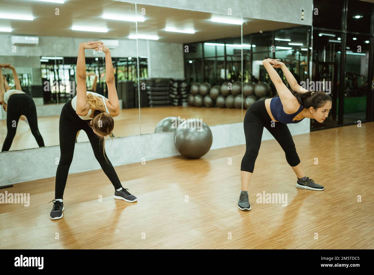 dos chicas en ropa deportiva estirando mientras van hacer ejercicio el gimnasio Fotografía de - Alamy