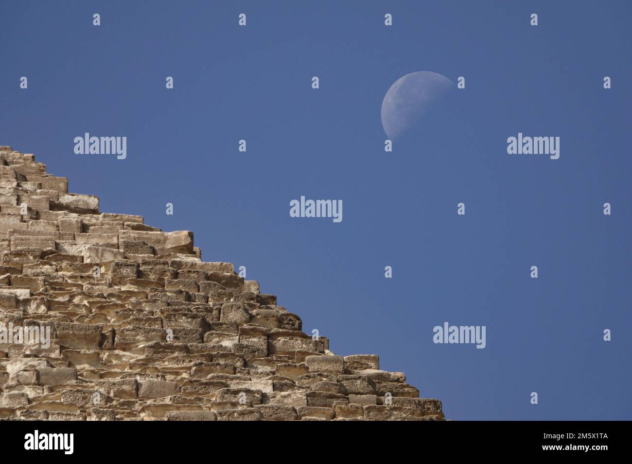 La luna vista detrás de la Pirámide de Khufu, la Gran Pirámide de Giza. Foto de stock