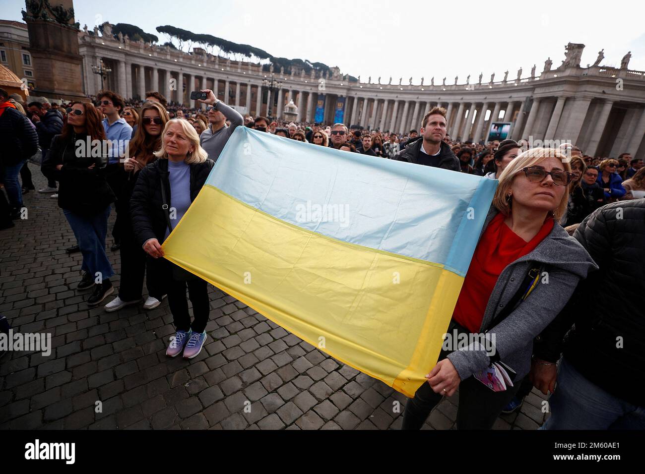 Los fieles sostienen una bandera ucraniana, mientras asisten a la oración  del Ángelus mientras la Iglesia Católica Romana celebra su Jornada Mundial  de la Paz, en el Vaticano, el 1 de enero