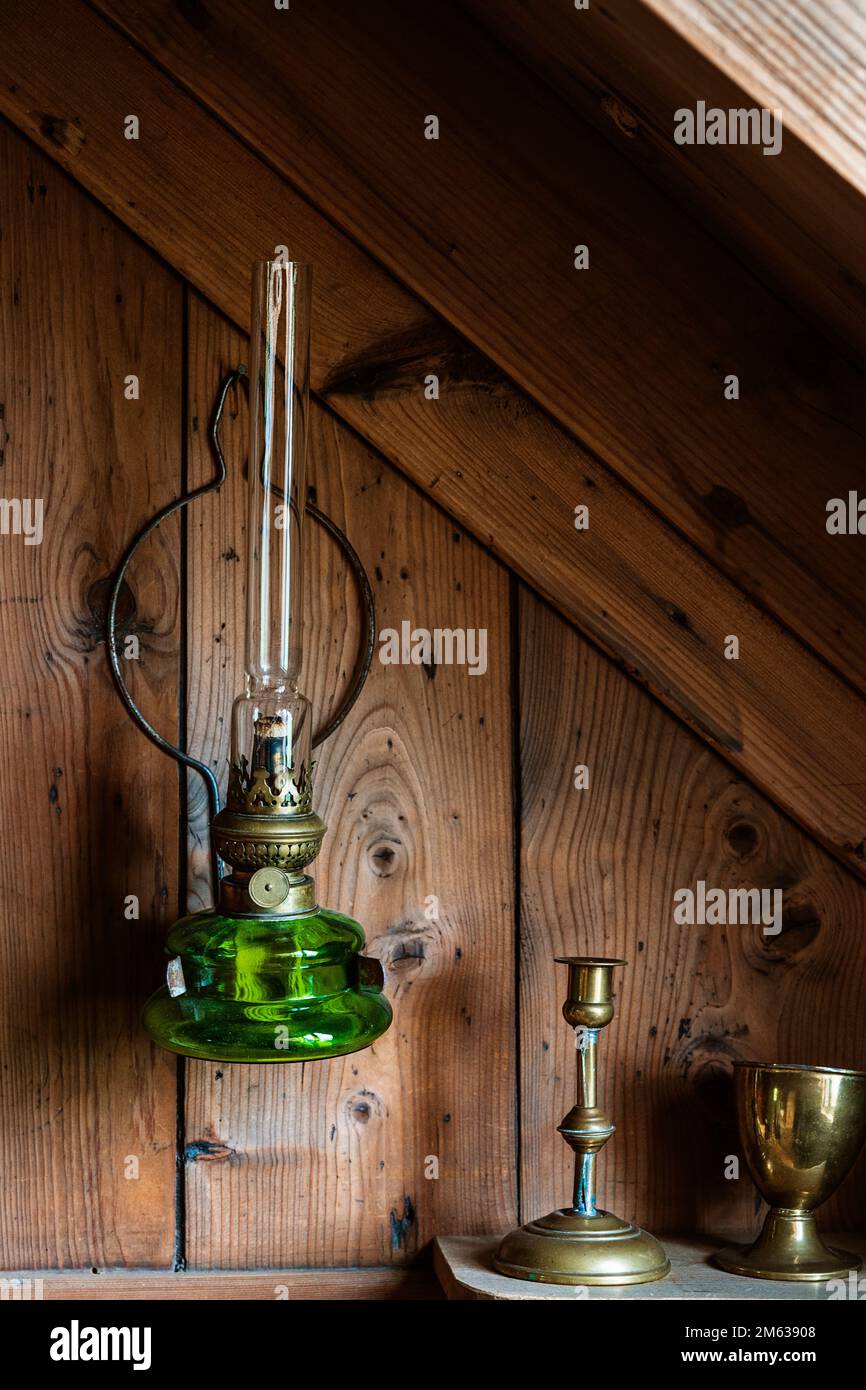 Lámpara de queroseno de vidrio verde vintage colgado en la pared de madera  con percha de metal cerca de utensilios de metal Fotografía de stock - Alamy