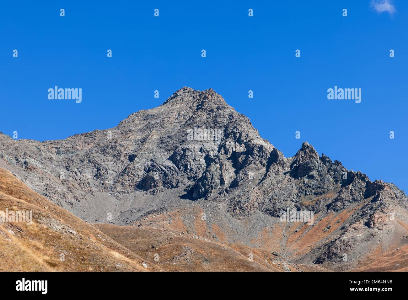 Granito inexpugnable ladera de montaña empinada negra y rocas afiladas con pico superior bajo fondo de cielo azul claro. Parque Nacional Gran Paradiso Foto de stock