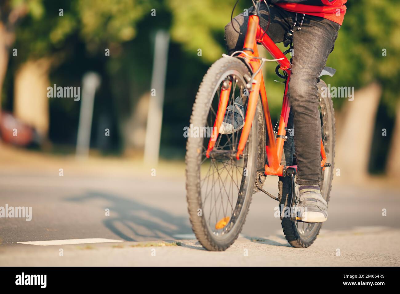 Niño montando una bicicleta en la acera a lo largo de la carretera de asfalto Fotografía de stock -