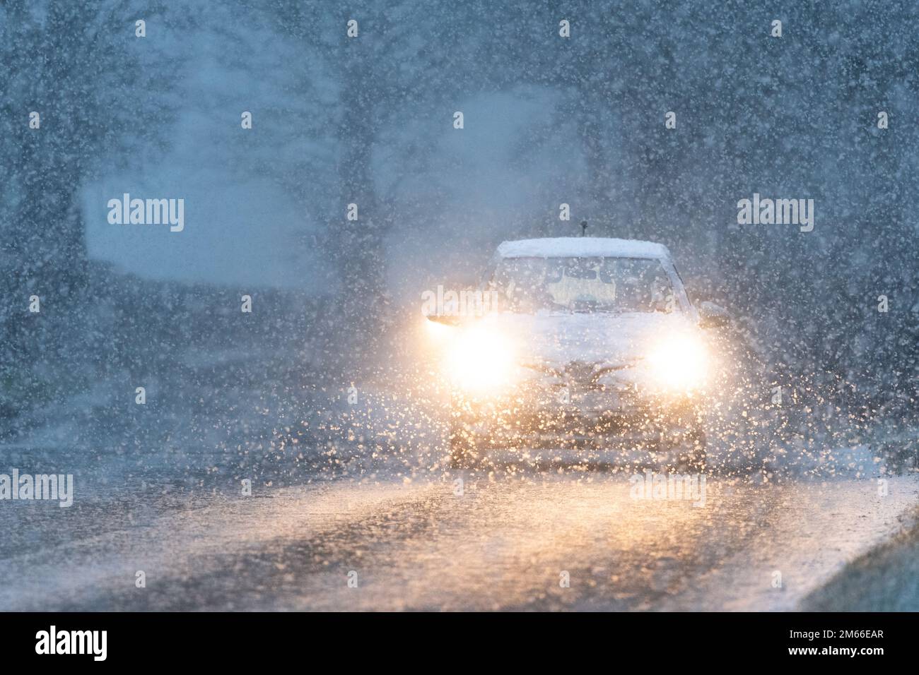 Coche de conducción en la nieve temprano por la mañana con los faros encendidos - Escocia, Reino Unido Foto de stock