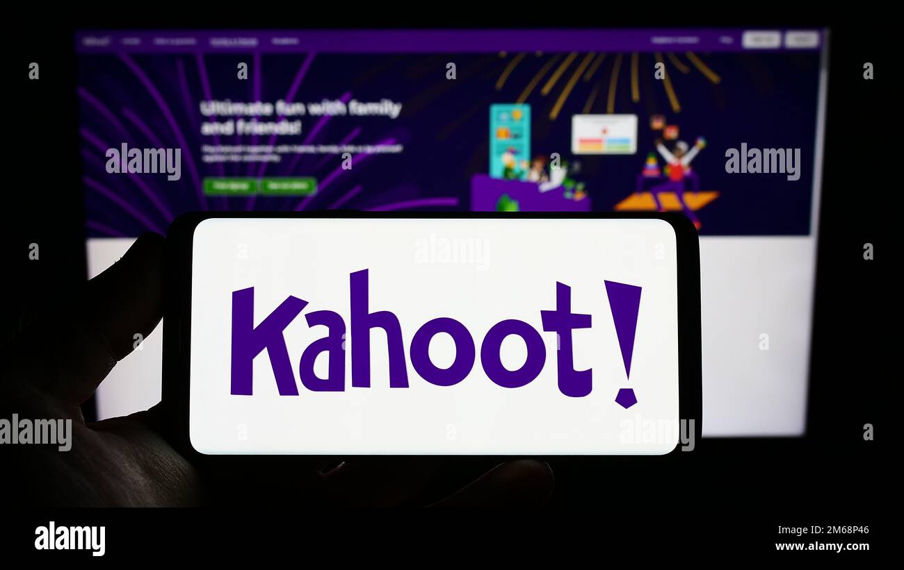 Persona que sostiene el teléfono inteligente con el logotipo de la empresa noruega de e-learning Kahoot en la pantalla frente al sitio web. Enfoque en la pantalla del teléfono. Foto de stock