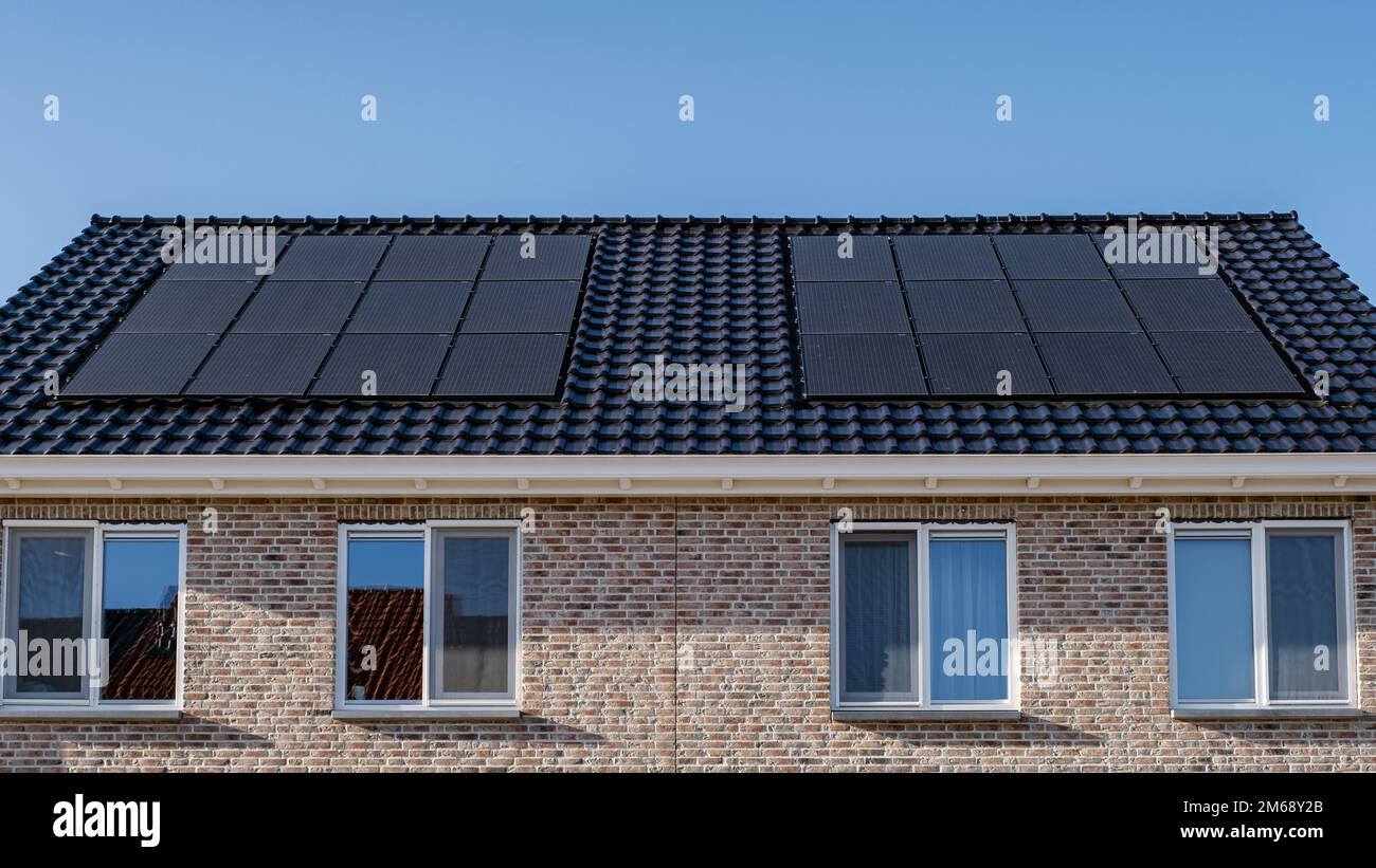 Casas de nueva construcción con paneles solares unidos en el techo contra  un cielo soleado, edificios nuevos con paneles solares negros.  Zonnepanelen, Zonne energie, Traducción: Panel solar Energía solar. Mercado  de la