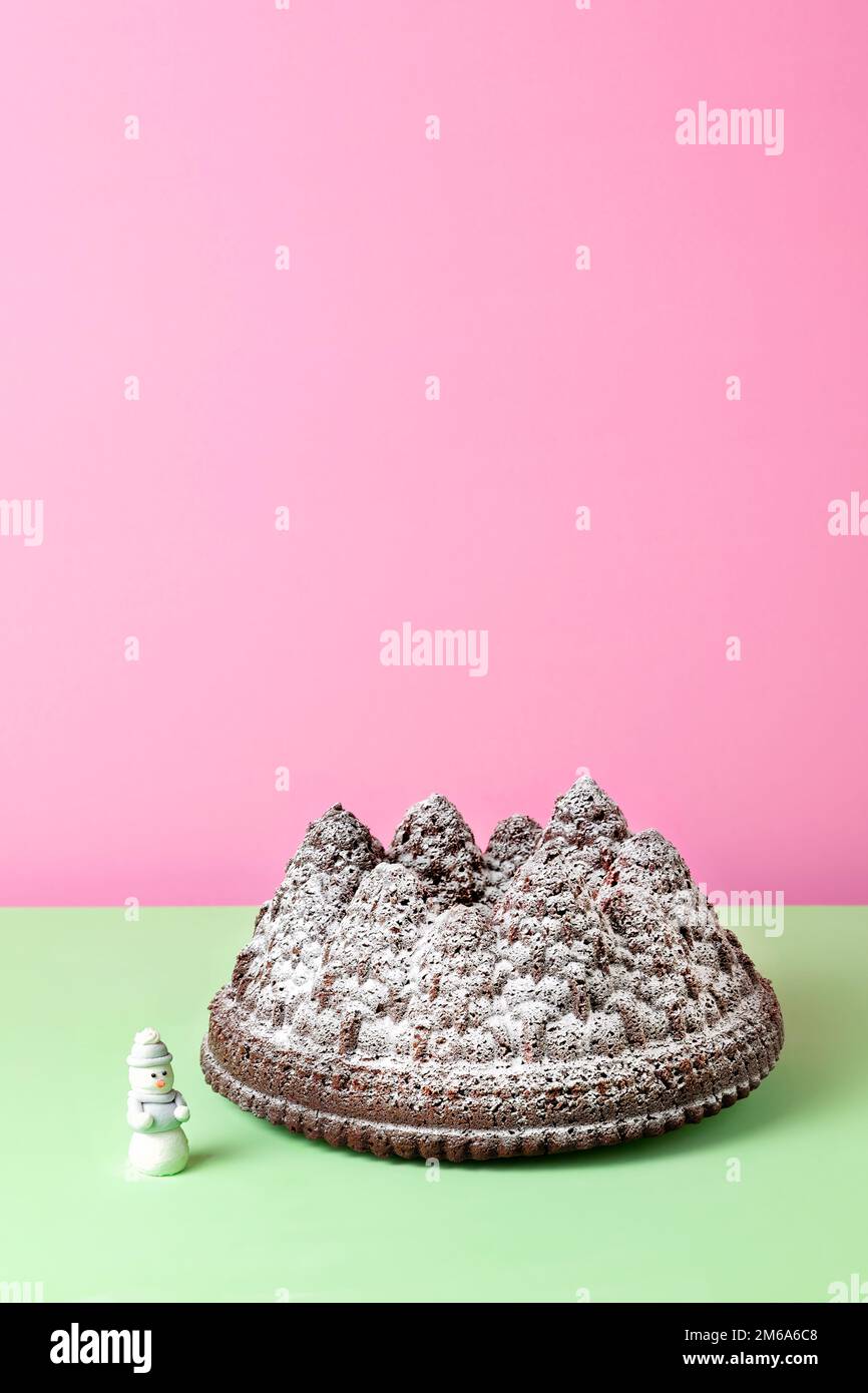 Un pastel de chocolate navideño festivo. El pastel se hace utilizando una lata Bundt para formar la masa de pastel en las formas de árbol. Una pizca de azúcar glasé lo cubre Foto de stock