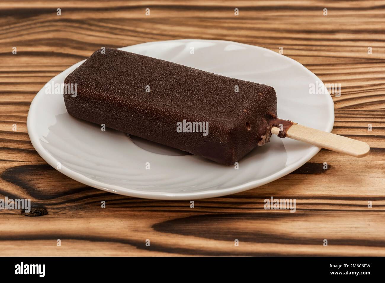 principal acceso lotería Sobre una mesa de madera, en un platillo es helado de chocolate glaze en un  palo Fotografía de stock - Alamy