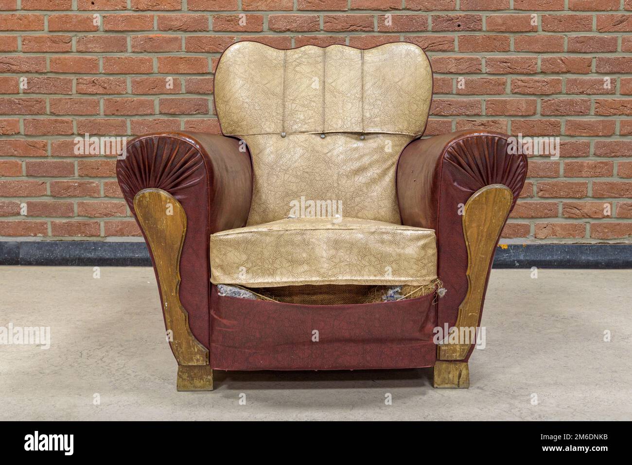 Un sillón con viejos rastros de tiempo contra una pared de ladrillo. formato cuadrado Foto de stock