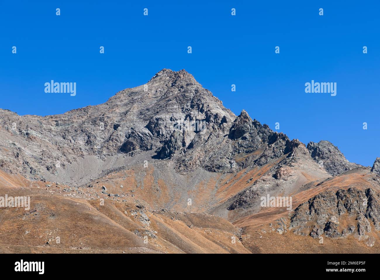 Ladera vertical del cuervo de granito infranqueable y rocas inclinadas con el pico negro superior bajo el fondo del cielo azul claro, valle de Aosta, Italia Foto de stock