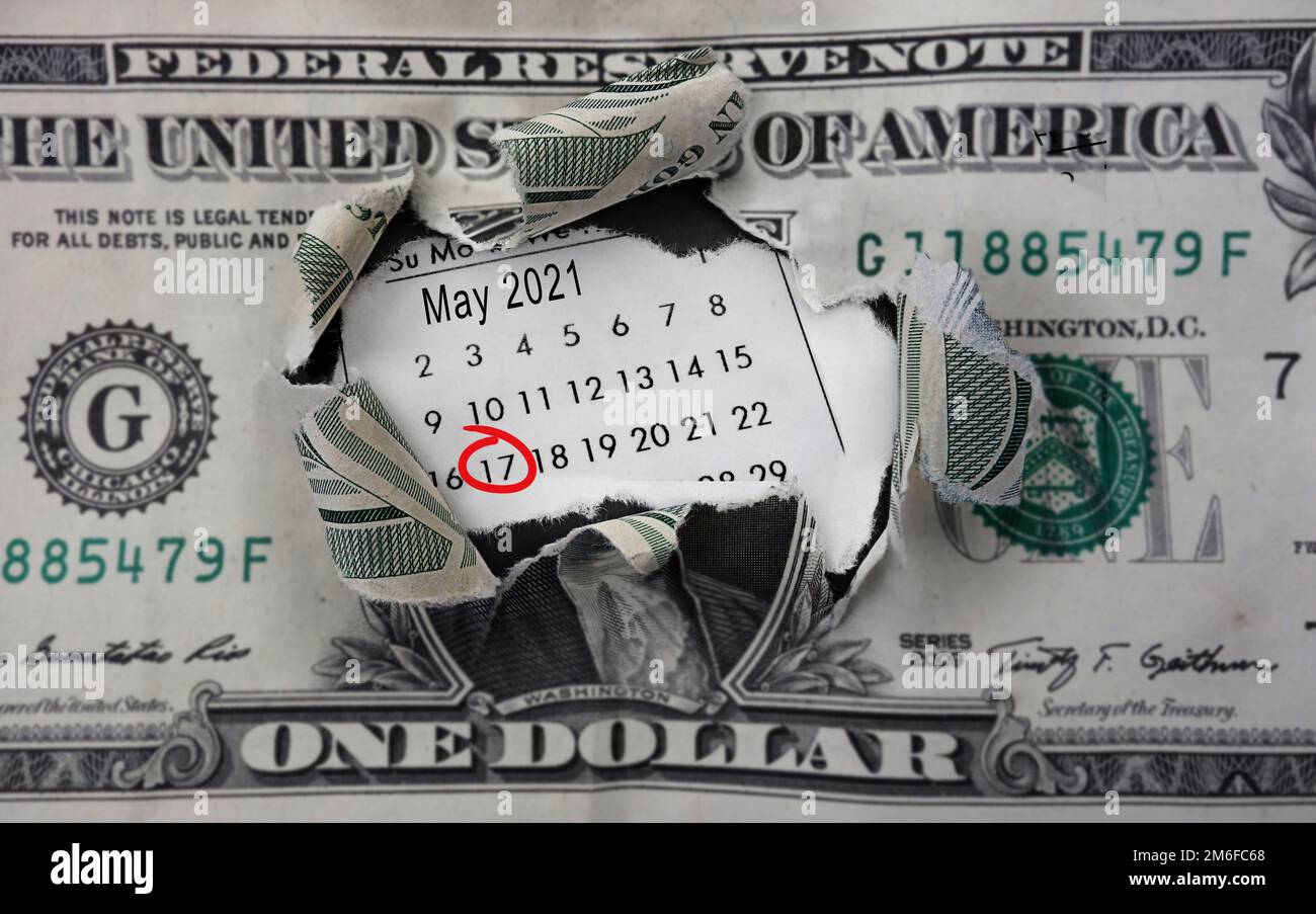 Dólar roto y calendario con el 17th 2021 de mayo en un círculo rojo, la fecha límite del IRS para pagar impuestos para 2021 Foto de stock