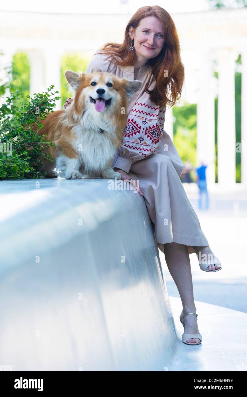 chica y hermoso perro corgi en la calle de la ciudad Foto de stock