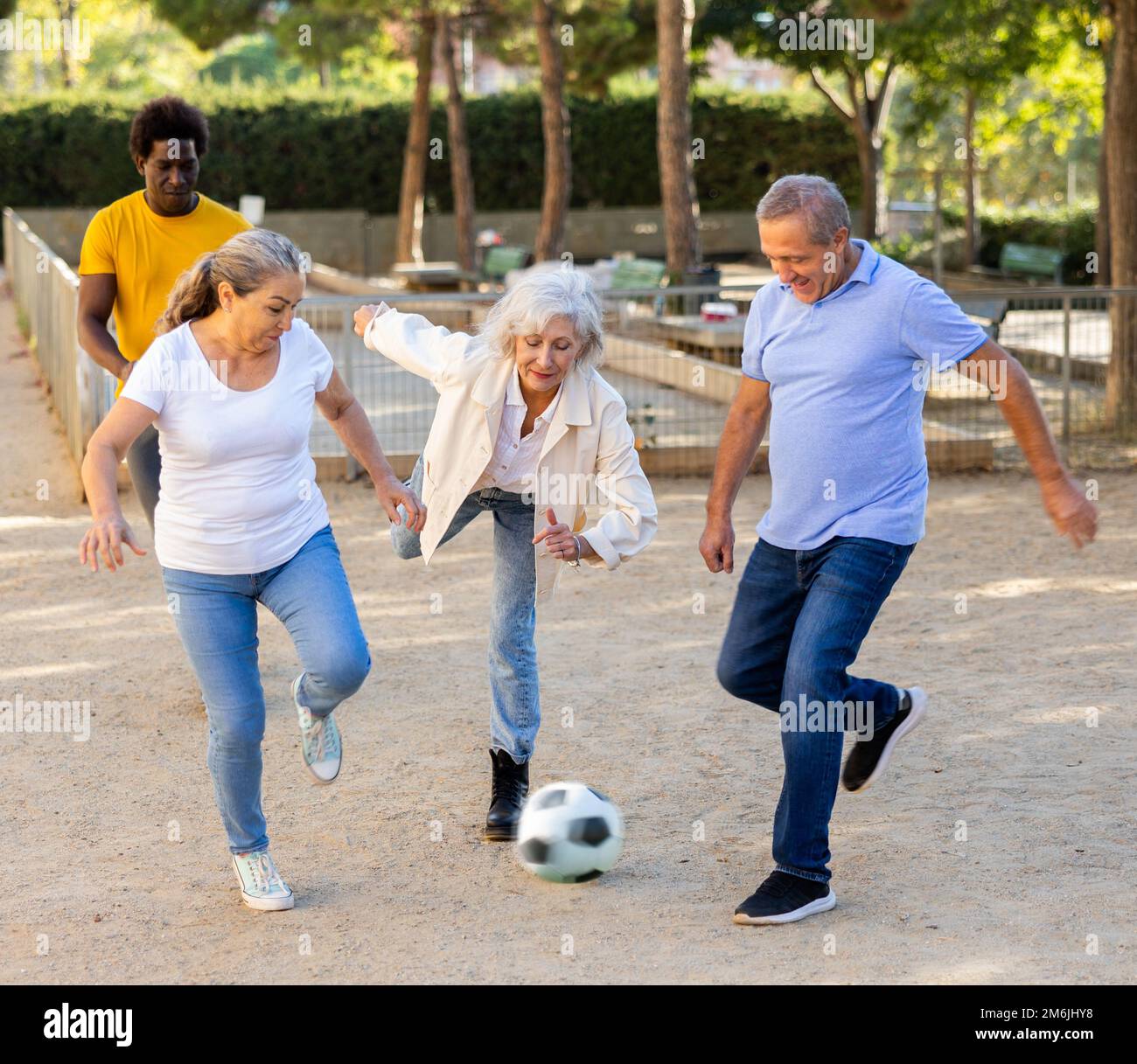 Hombres y mujeres alegres pateando la pelota en el parque Fotografía de  stock - Alamy