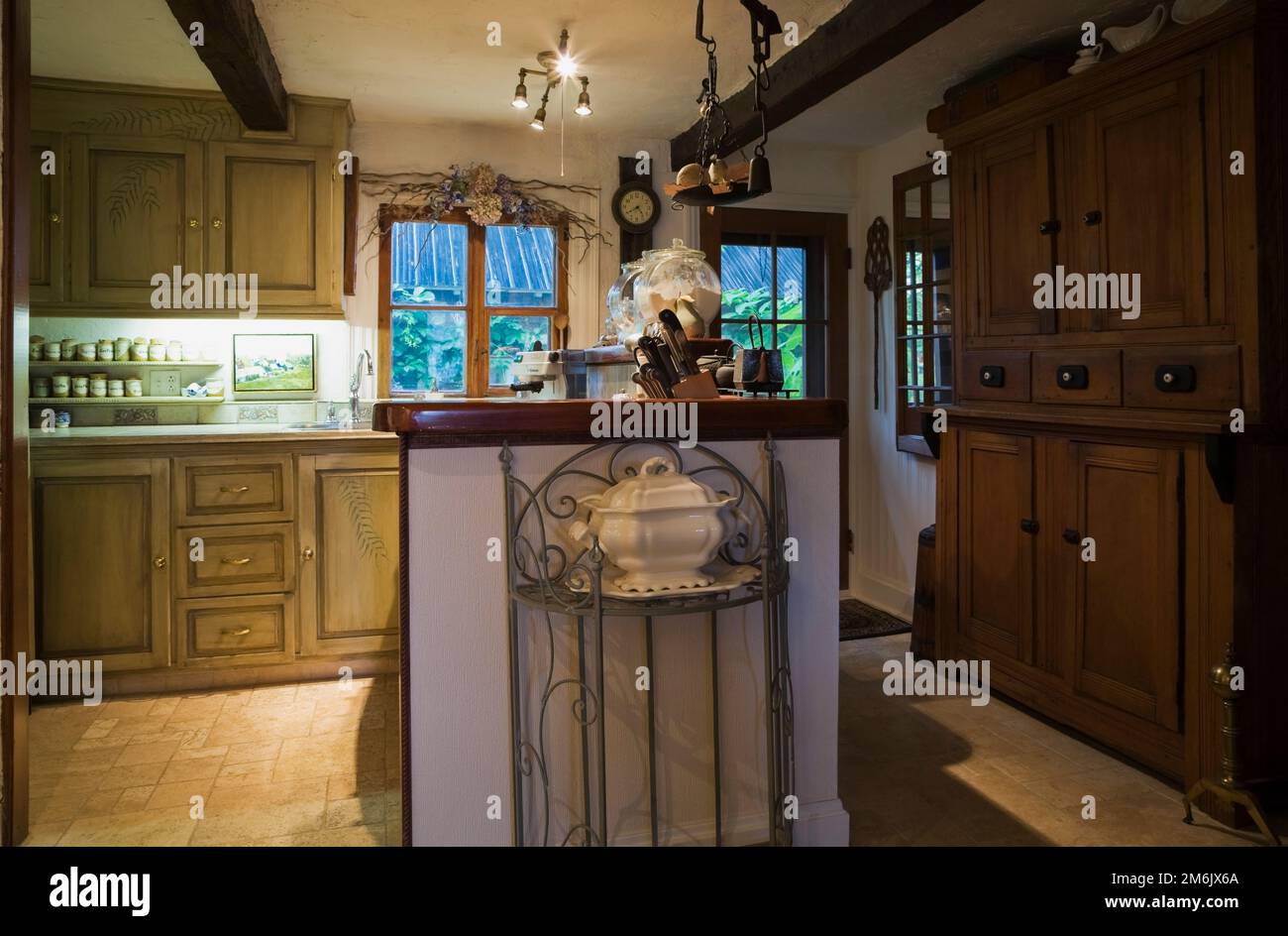 Isla de cocina rural con gabinetes de madera y buffet antiguo marrón dentro de la antigua casa estilo cabaña de 1809. Foto de stock