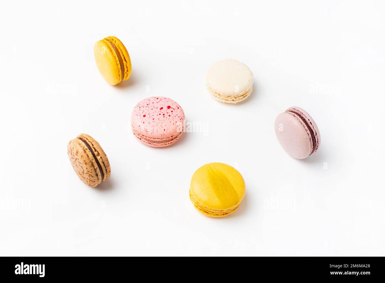 Macarrones comida dulce sobre fondo blanco. Amarillo pastel, fondo de color rosa. Foto de stock