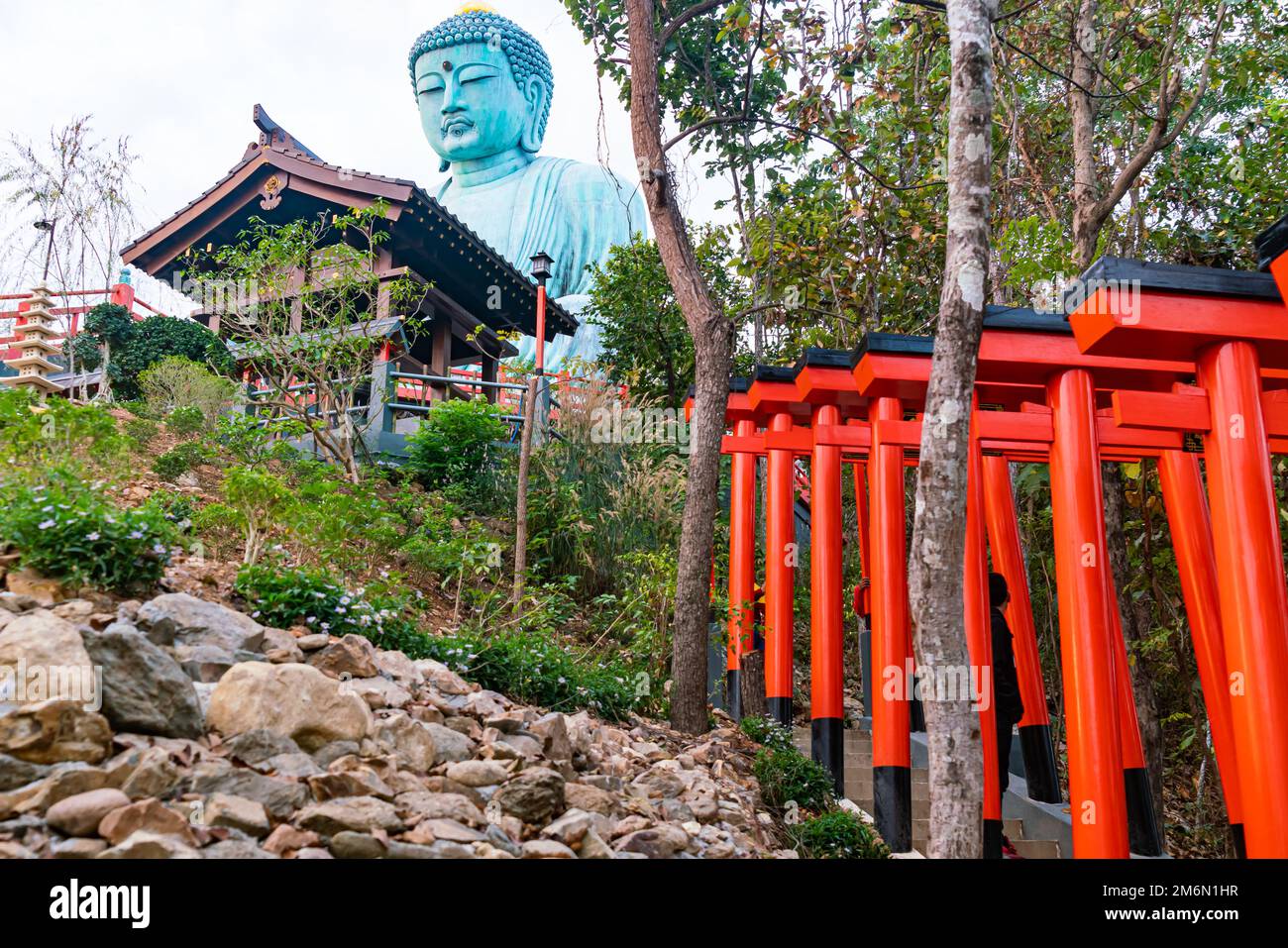 Estatua de Buda sentado en la montaña en Doi Phra Chan en la provincia de Lampang con el Torii rojo y el edificio de madera. Foto de stock