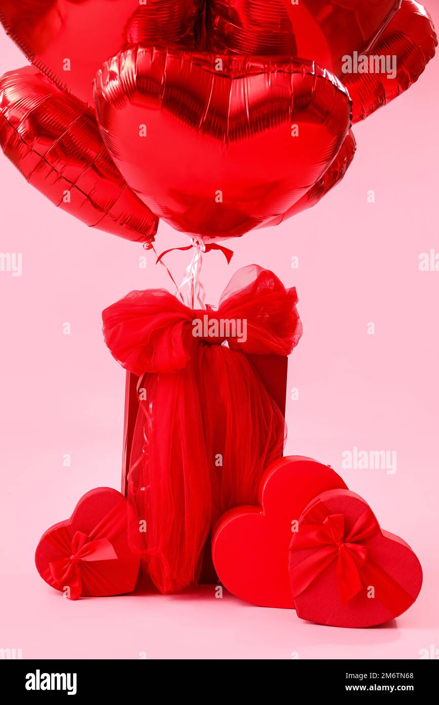 Regalos con arco y globos para el día de San Valentín sobre fondo rosa  Fotografía de stock - Alamy