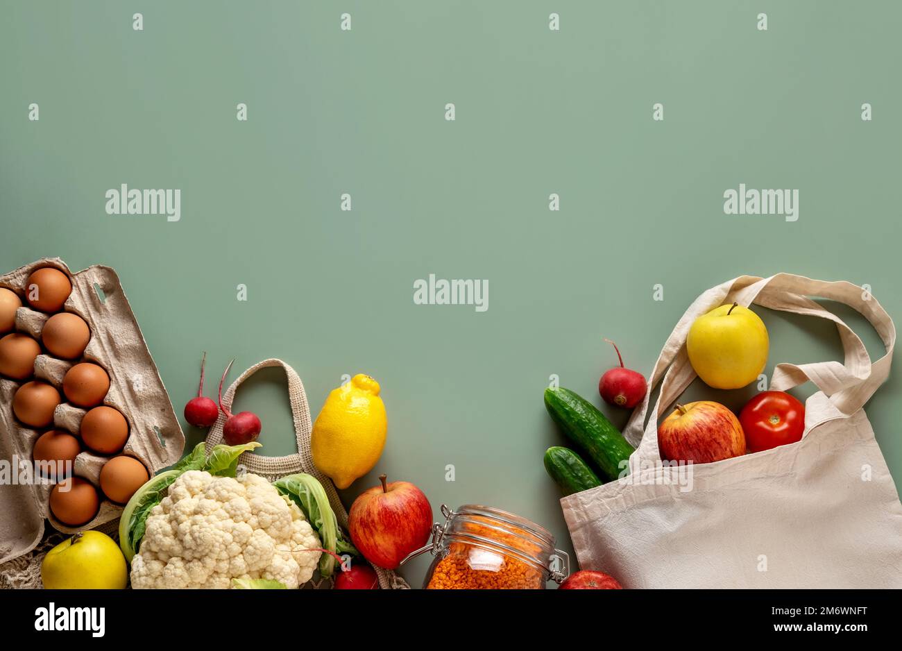 Concepto de compra de residuos cero sobre fondo verde. Verduras y frutas frescas en bolsas de algodón ecológico en la mesa. Foto de stock