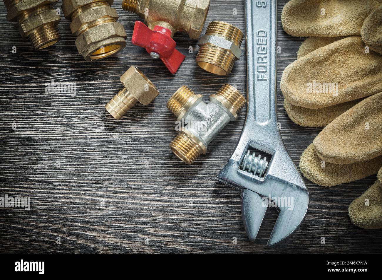 Llave ajustable válvula de agua accesorios de tubería guantes de seguridad  en tabla de madera Fotografía de stock - Alamy