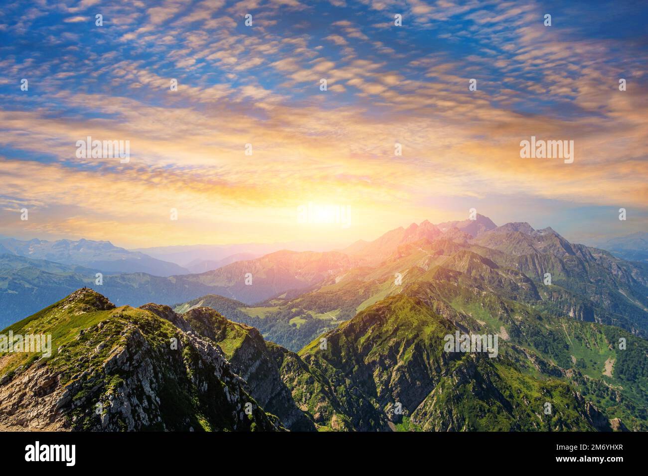 Panorama de una cadena montañosa con prados alpinos durante la puesta del sol con hermoso cielo nublado Foto de stock