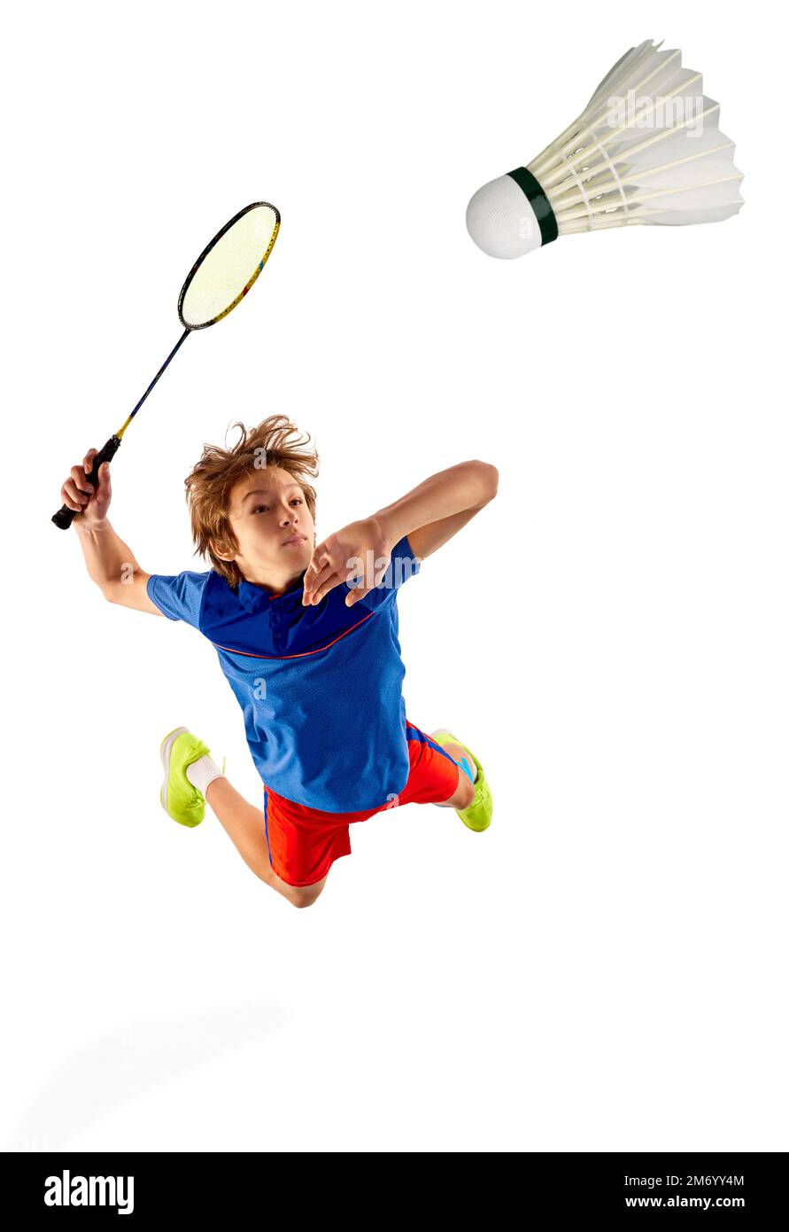 Vista superior. Niño adolescente motivado en uniforme jugando bádminton, golpeando shuttlecock con raqueta en un salto aislado sobre fondo blanco Foto de stock