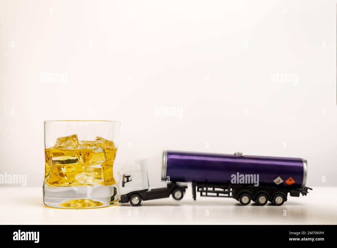 Camión cisterna de juguete con etiquetas de mercancías peligrosas que  chocan en un vaso con whisky, incompatibilidad de conducción profesional y  alcohol Fotografía de stock - Alamy