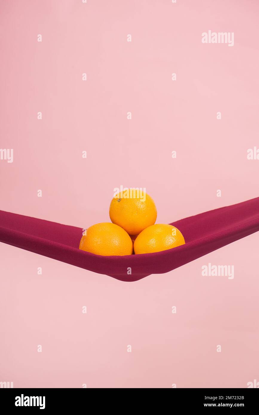 cuatro naranjas cortadas por la mitad en un paño rojo delante de un fondo de melocotón como símbolo del suelo pélvico, no hay gente Foto de stock