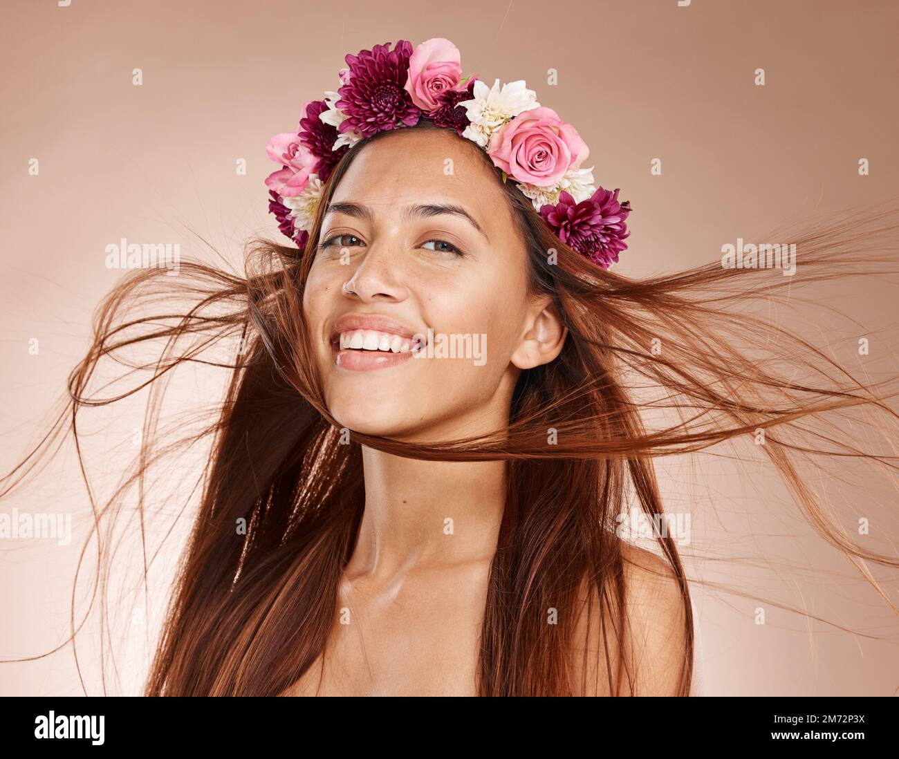 Mujer, retrato y flores en la corona, fondo de estudio y cabello ventoso para el cuidado de la piel saludable en Brasil. Cara feliz, diadema floral y modelo de belleza Foto de stock
