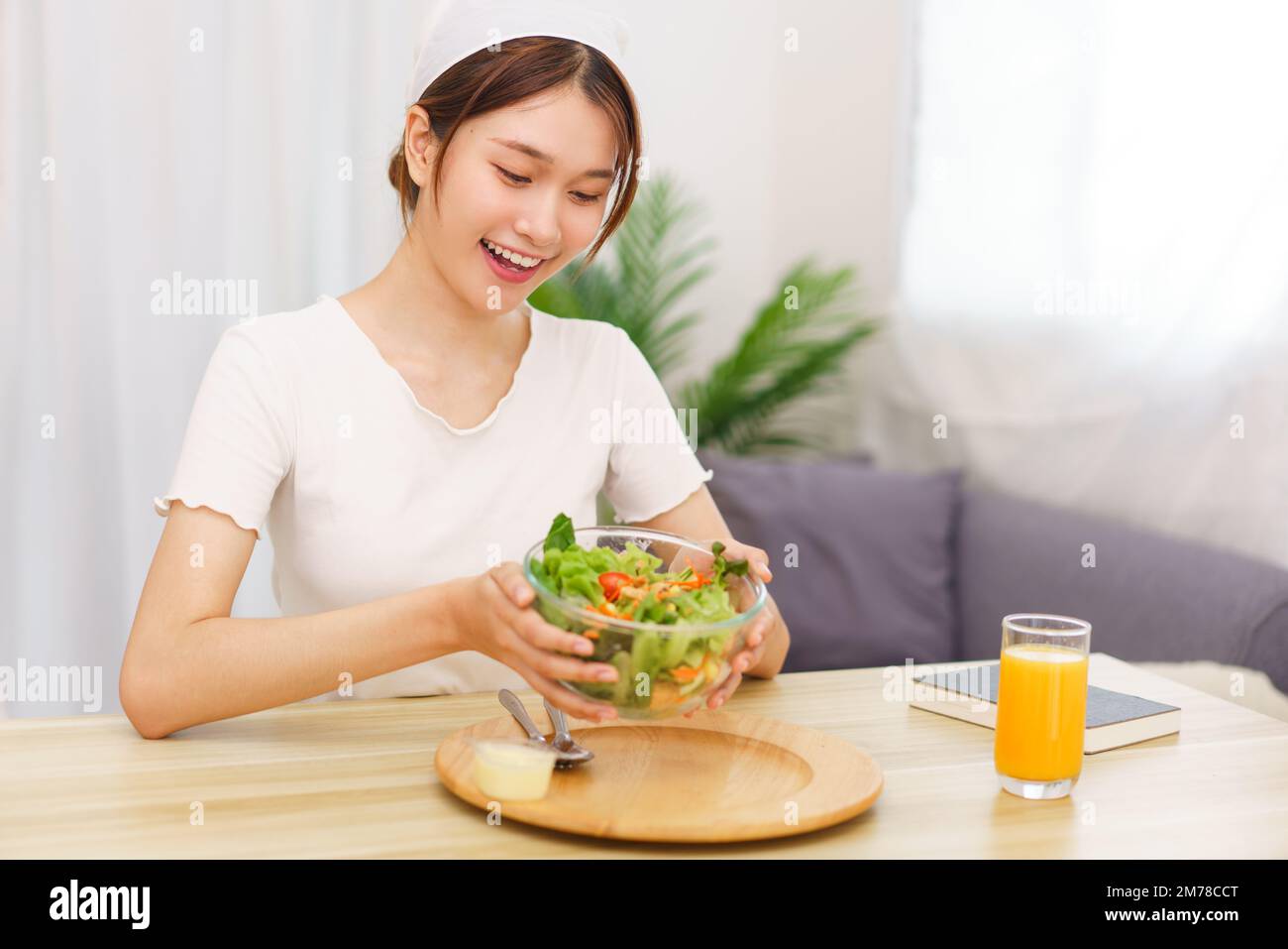 Estilo de vida en el concepto de sala de estar, mujer asiática joven sonriendo y sosteniendo un tazón de ensalada de verduras. Foto de stock