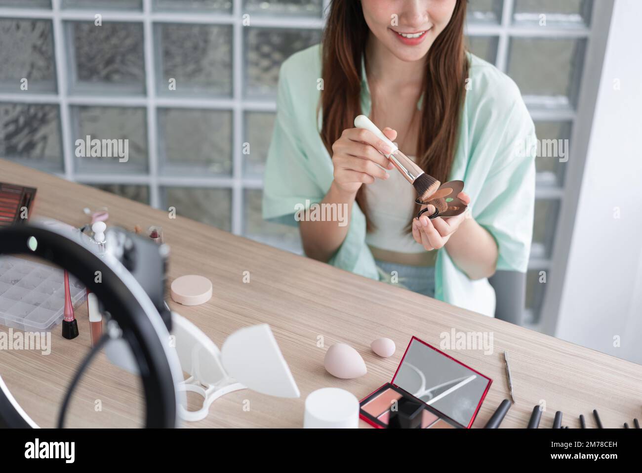 Belleza blogger concepto, uso de la mujer joven cepillo con base líquida para aplicar y revisar en Vlog. Foto de stock