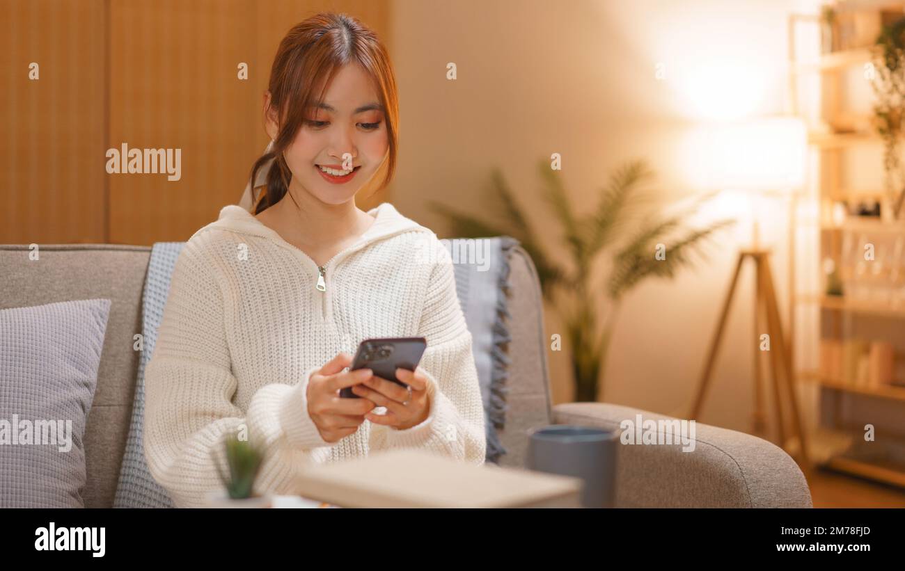Concepto de vida nocturna, mujer joven que navega las redes sociales en el teléfono inteligente en la noche en invierno. Foto de stock